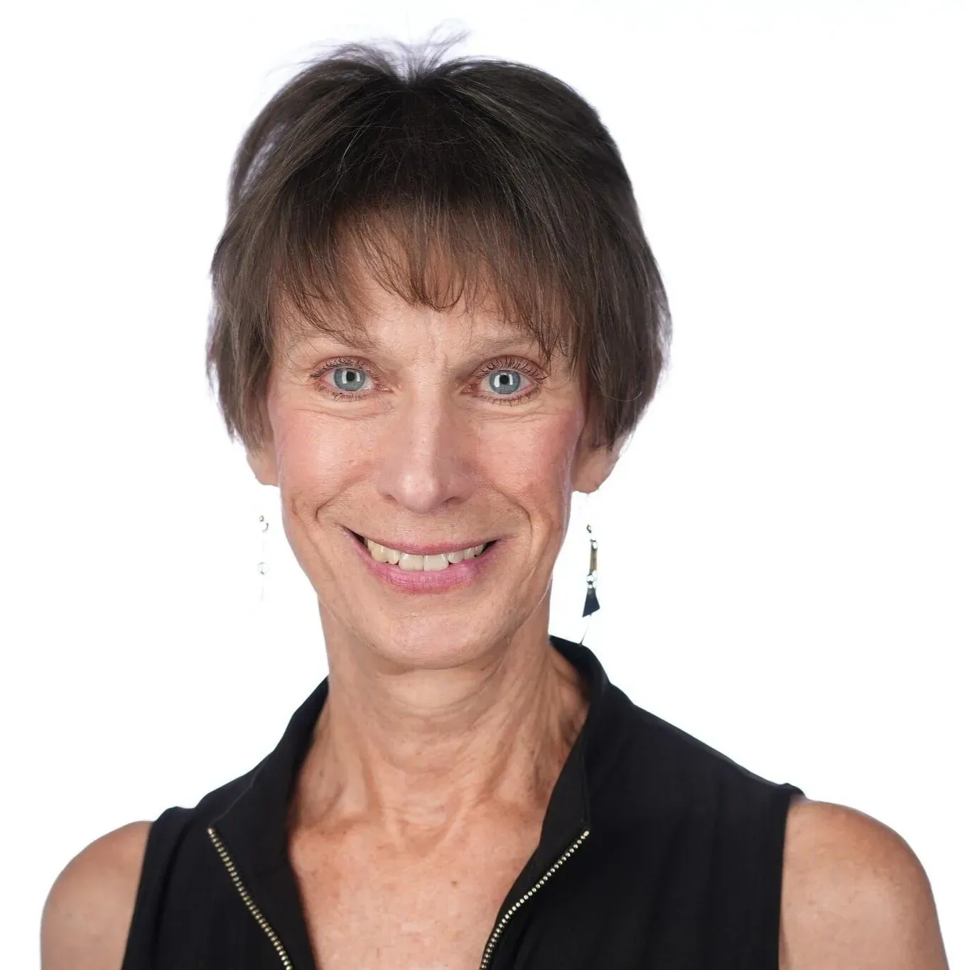 Woman with short brown hair, blue eyes, smiling, wearing a black top, studio shot.