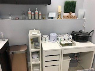 A room with a desk , drawers , shelves , a trash can and a pot.