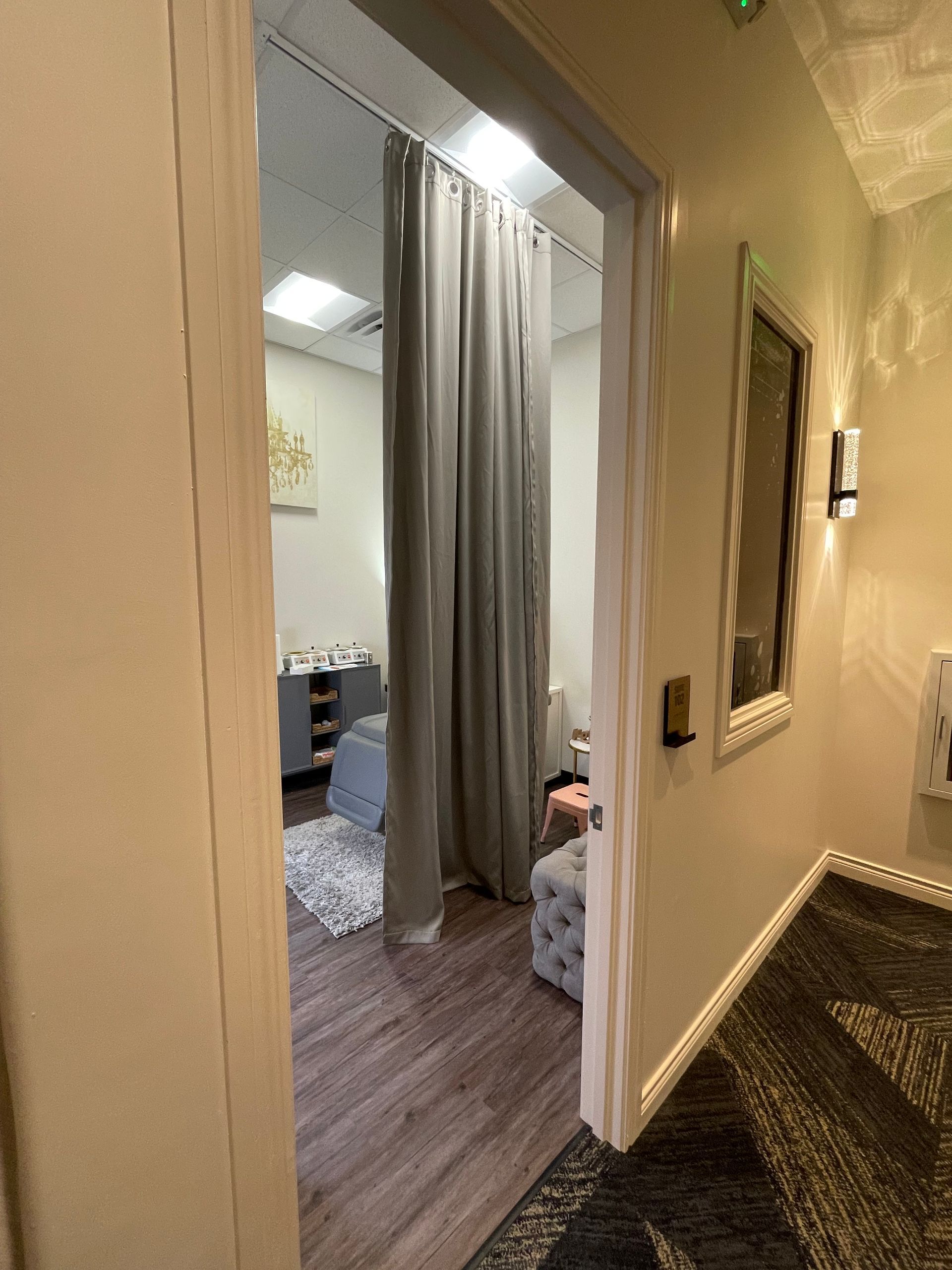 A hallway leading to a room with a curtain and a mirror.