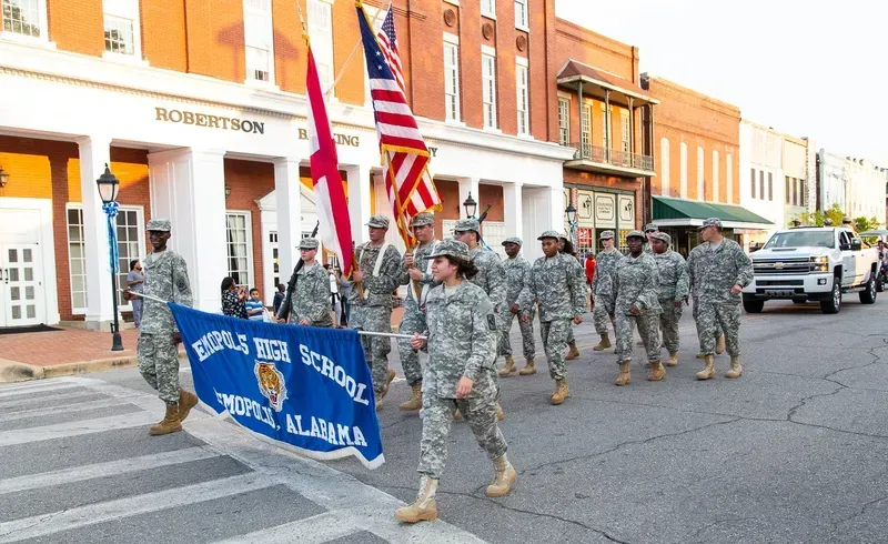 A group of soldiers are marching down a street in a parade.
