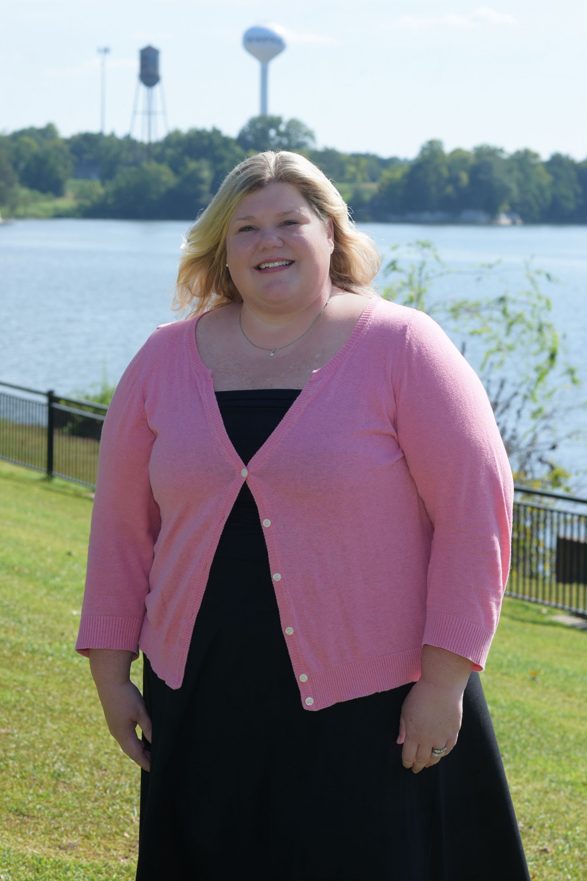 A woman with blonde hair is wearing a black shirt and smiling.