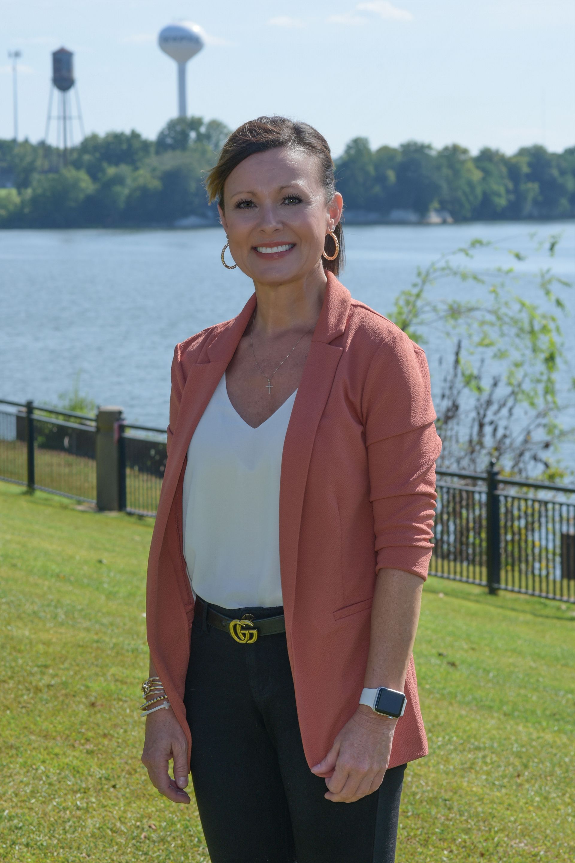 A woman wearing a black shirt and a cross necklace is smiling for the camera.