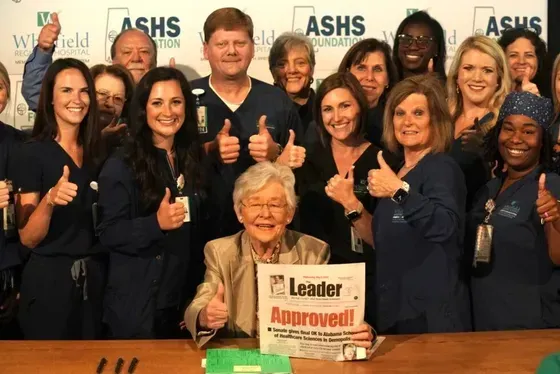 A group of people giving a thumbs up with a sign that says leader approved