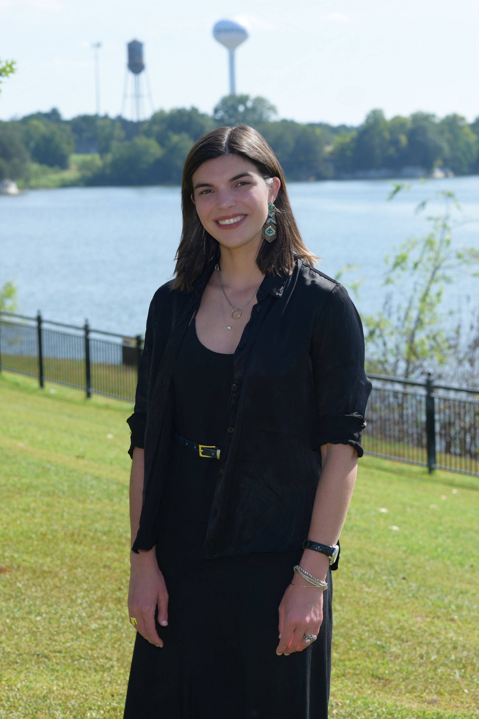 A woman wearing a black shirt and a silver necklace smiles for the camera