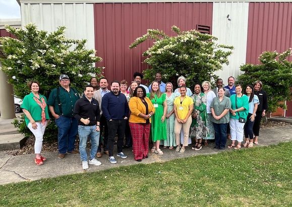 A group of people are standing next to each other in front of a building.