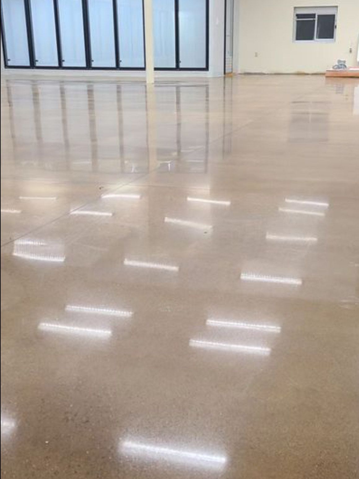 A large empty room with a shiny floor and a window.