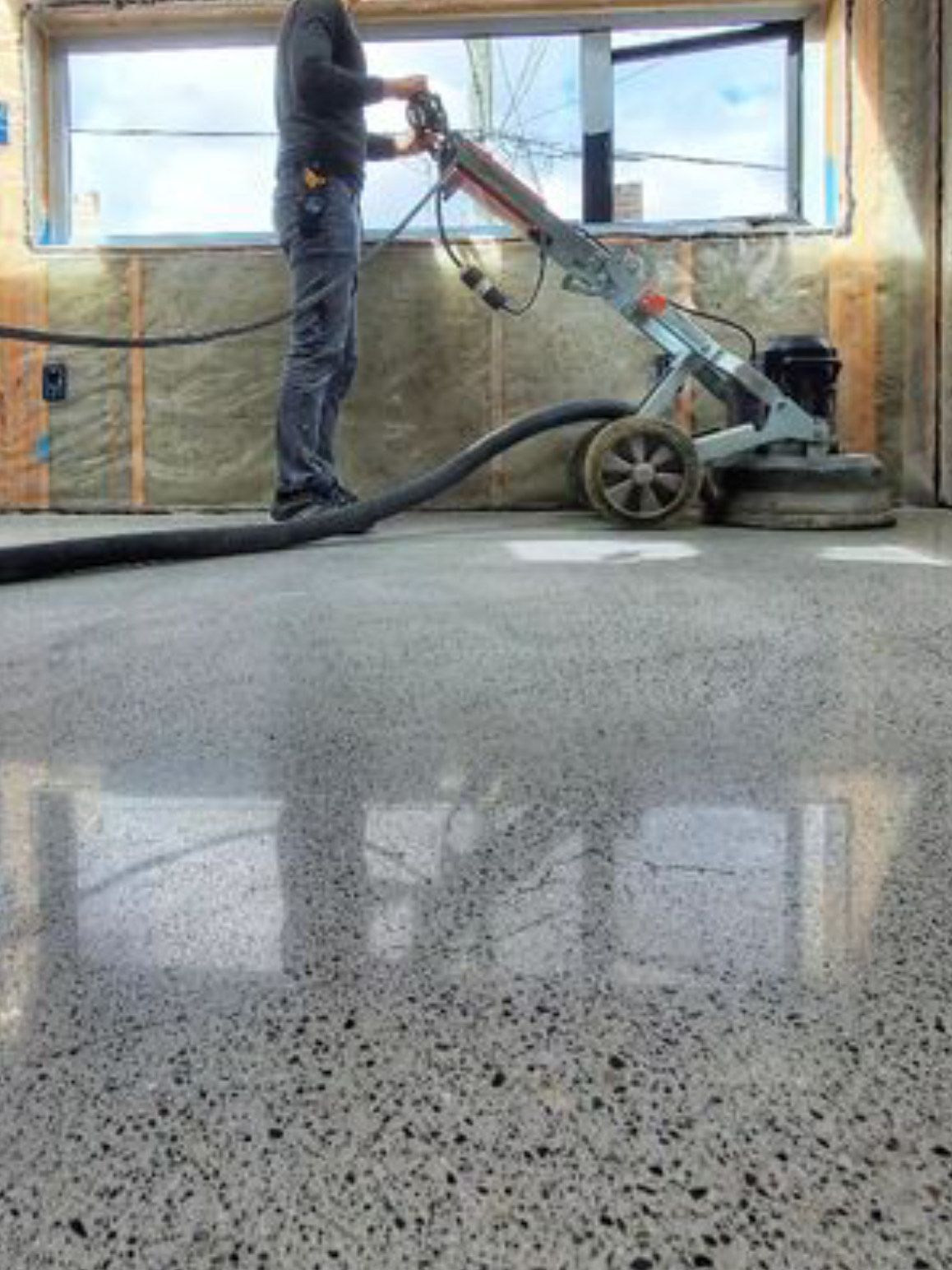 A man is polishing a concrete floor with a machine.