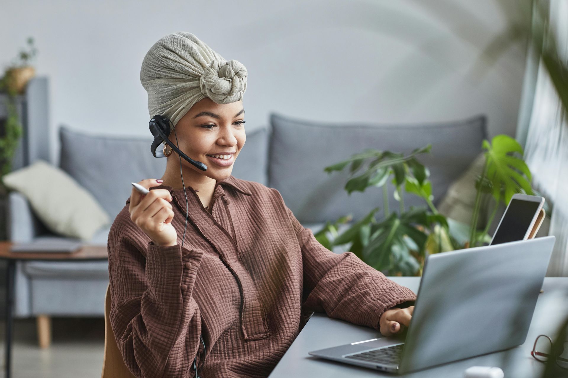 A woman wearing a headset is sitting in front of a laptop computer.