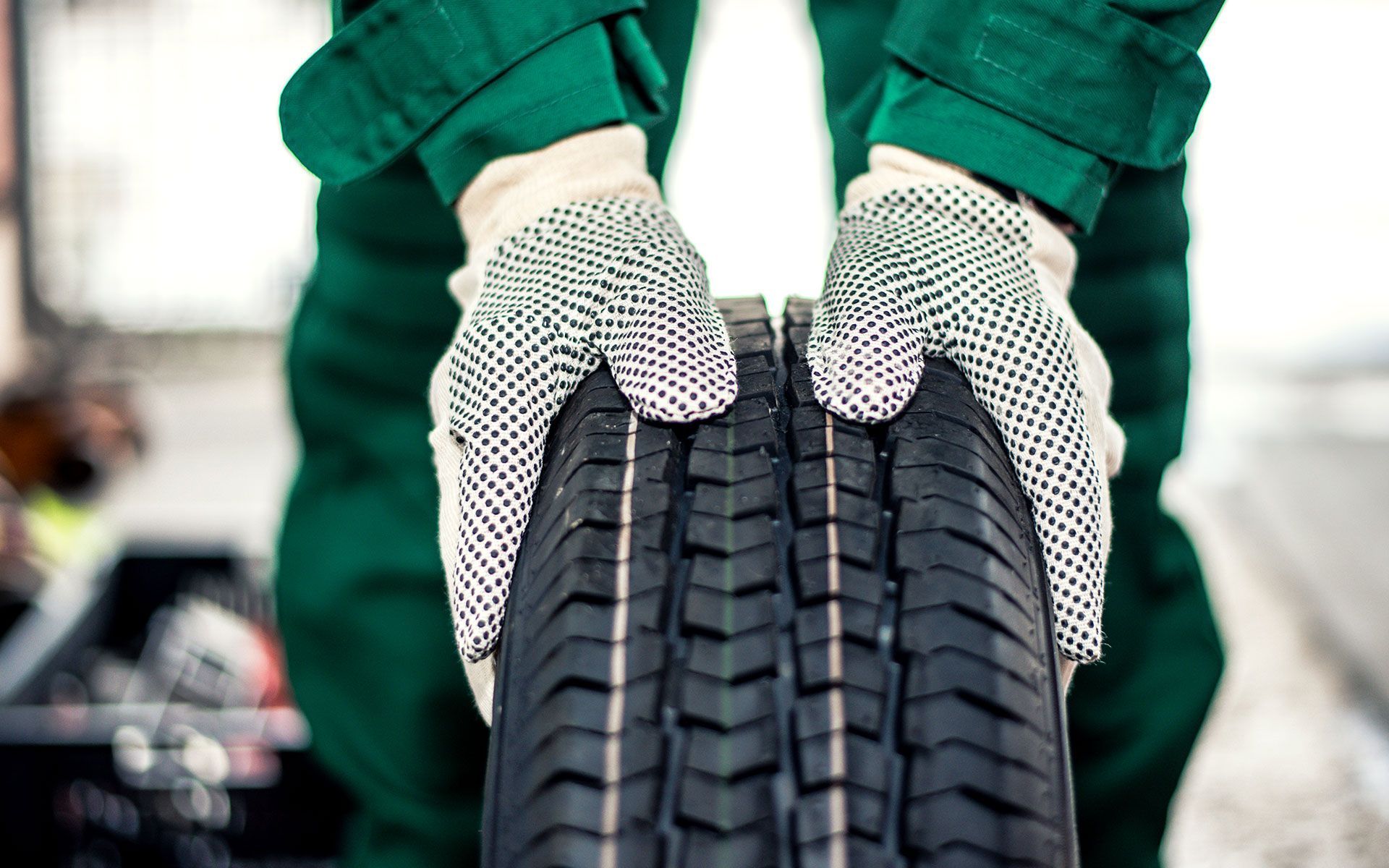 A person wearing gloves is holding a tire in their hands.