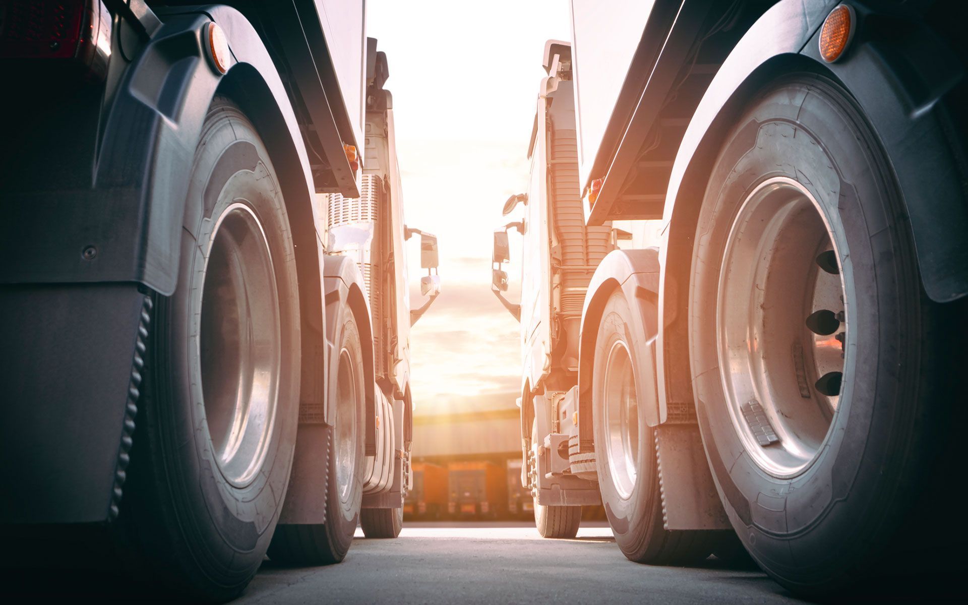 A row of semi trucks are parked next to each other in a parking lot.