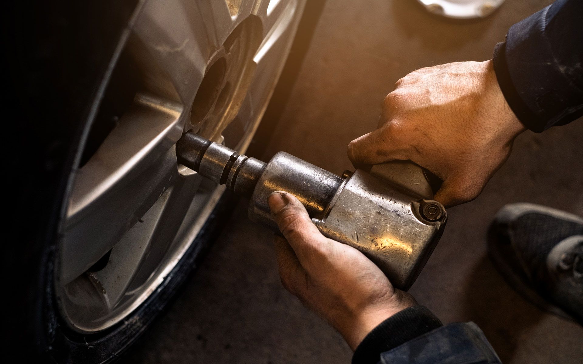 A man is using an air wrench to change a tire on a car.