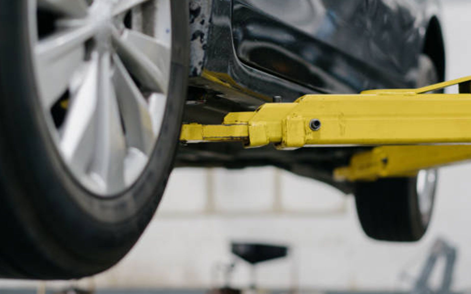 A car is being lifted on a yellow lift in a garage.