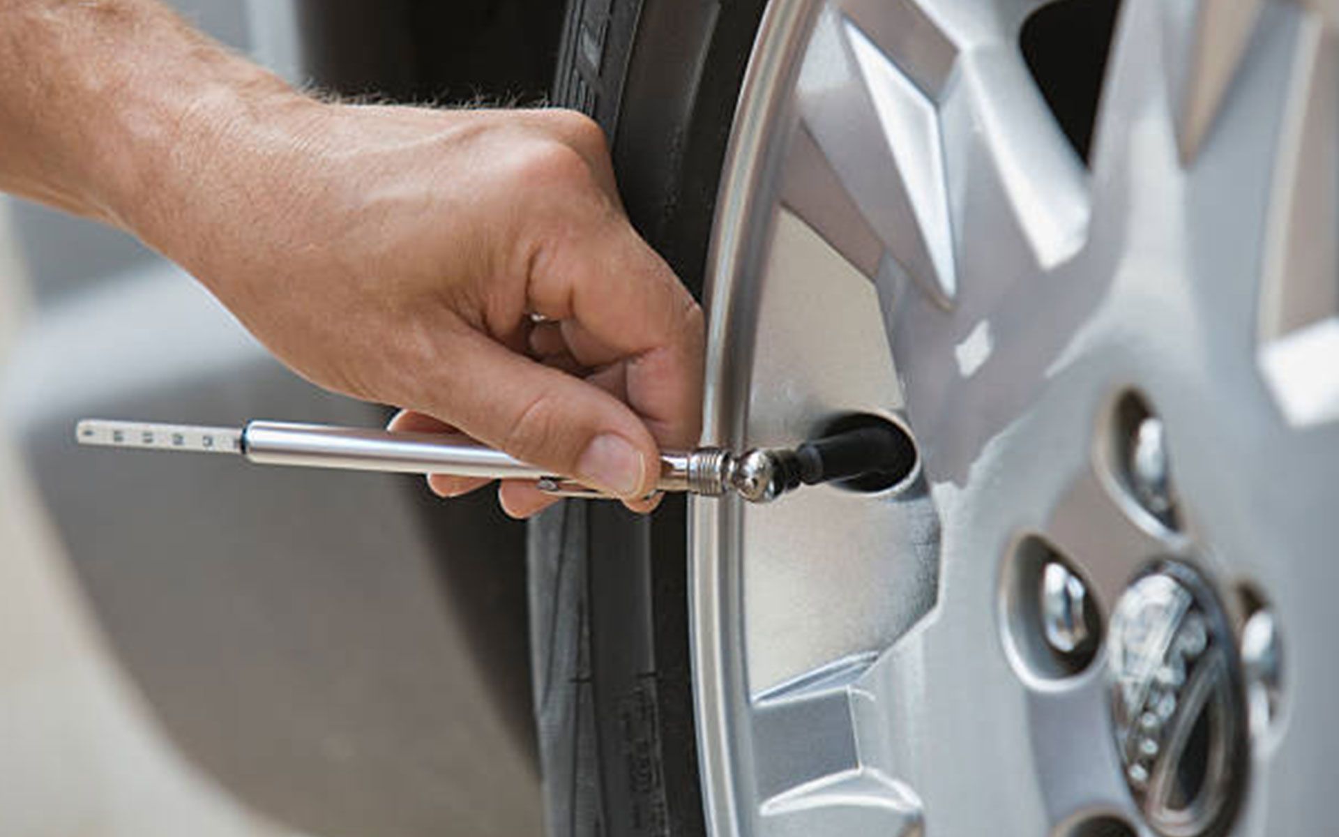 A person is checking the pressure of a tire with a gauge.