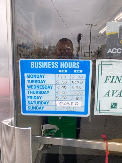 A man is standing in front of a business hours sign.