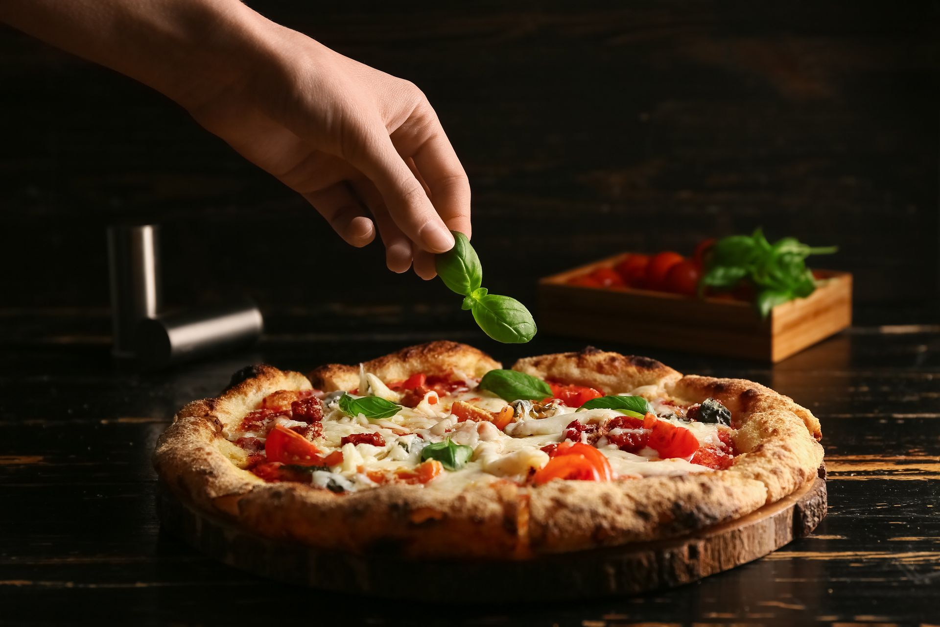 Hand sprinkling basil on a pizza