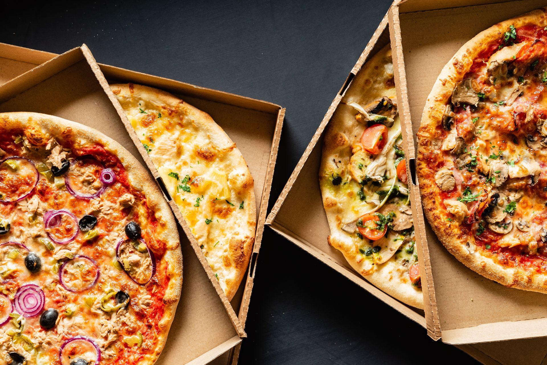 Four pizzas in open cardboard boxes