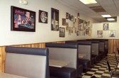 Restaurant interior with booths, checkered floor, framed art on wall.