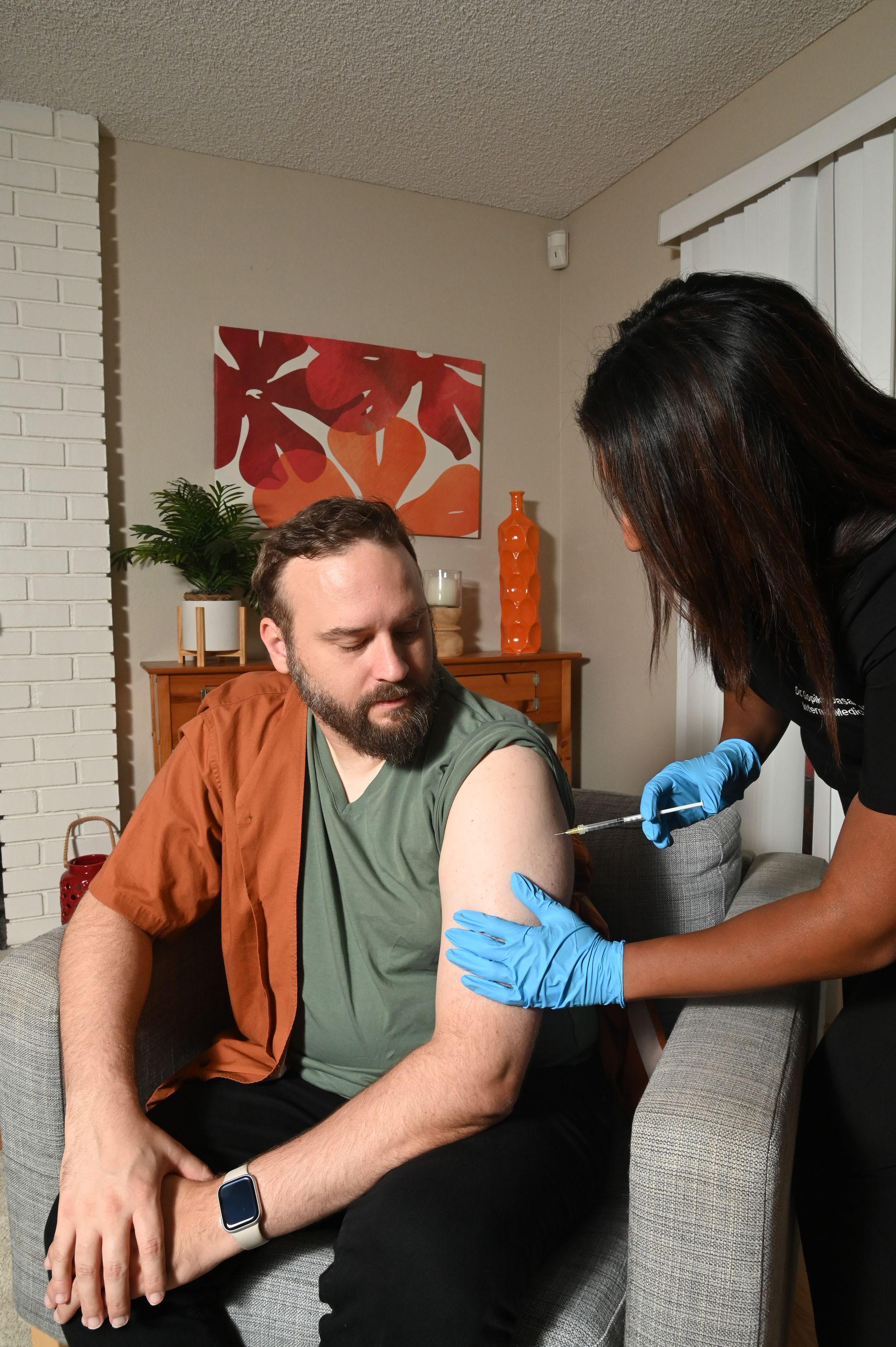 A woman is examining a man 's chest in a living room.