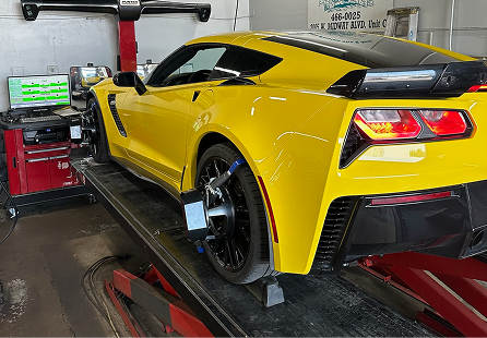 Yellow Corvette on an alignment rack in a shop. Black wheels, rear lights on. | Rocky Mountain Car Care