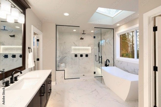 A finished custom bathroom renovation featuring brown cabinets, marble, a shower, and a tub.