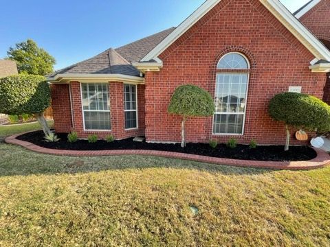 A brick house with a lush green lawn in front of it.