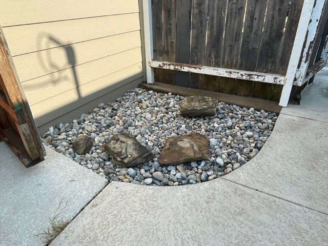 A pile of rocks on a sidewalk next to a wooden fence