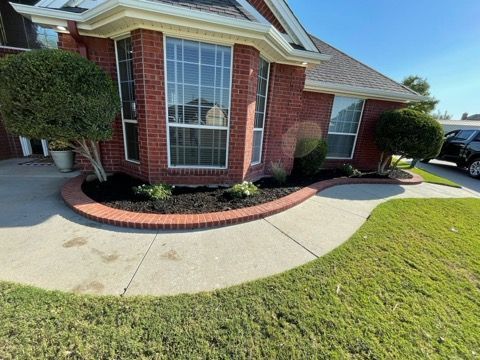 A brick house with a lush green lawn and a sidewalk in front of it.