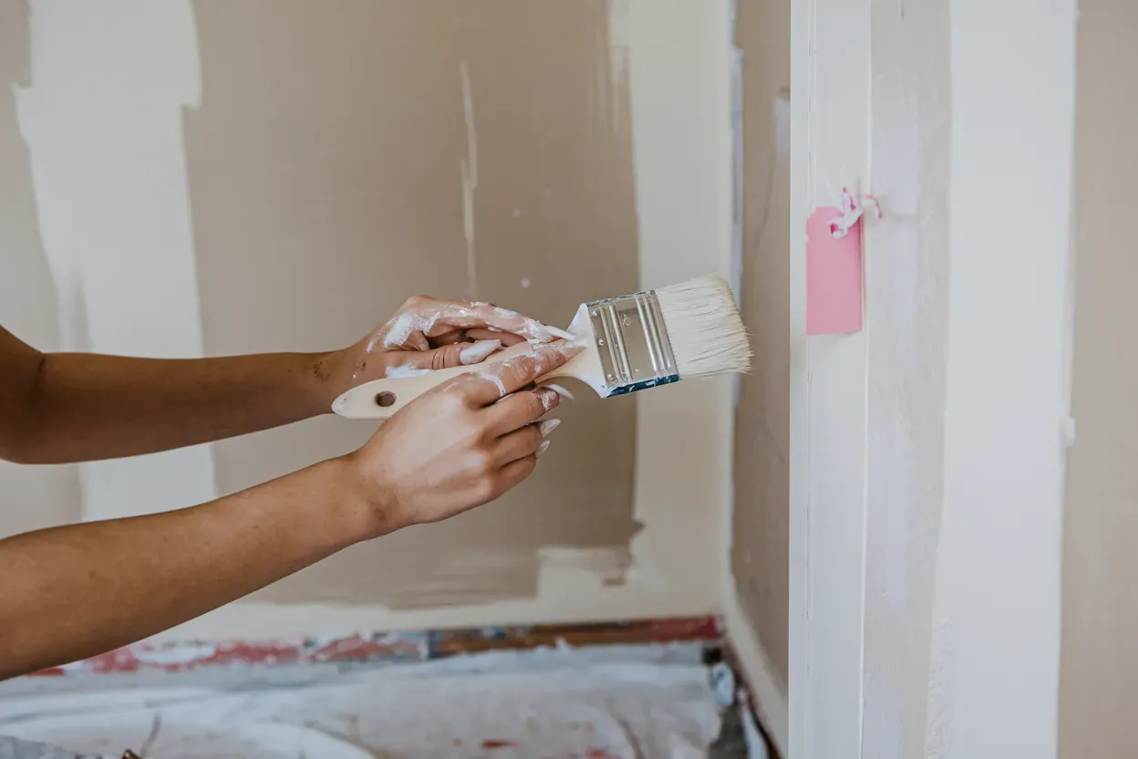 A person is painting a wall with a brush.