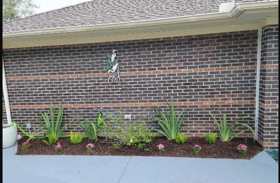 A brick wall with a garden in front of it.
