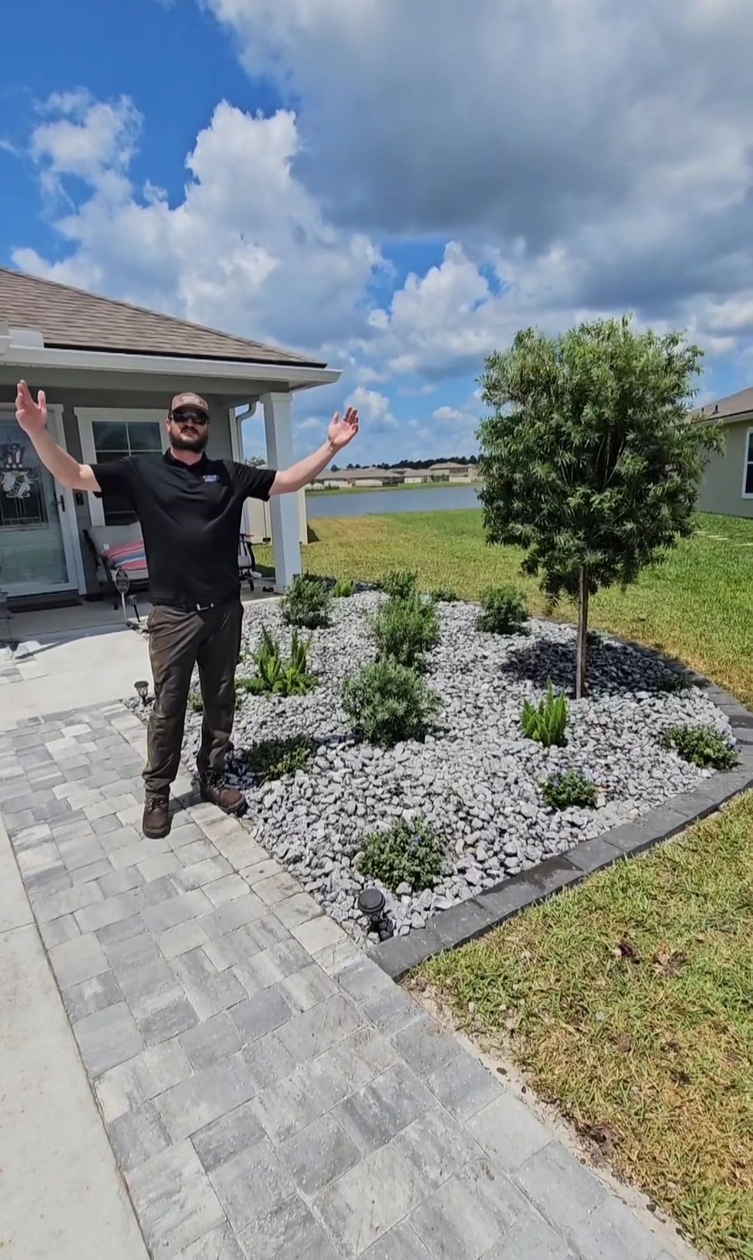 A man is standing in front of a house with his arms outstretched.