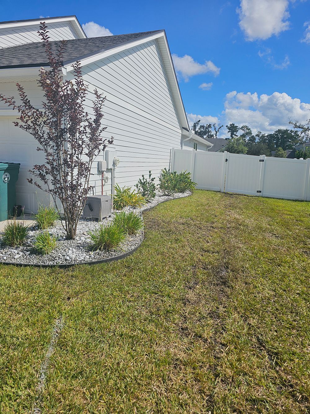 A house with a white fence and a lush green lawn in front of it.