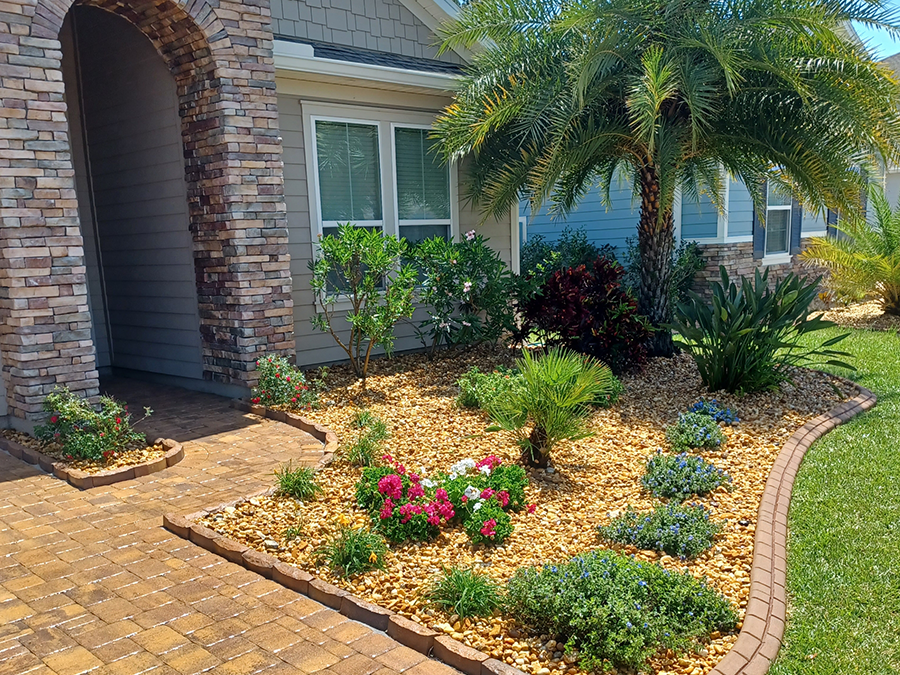 A house with a brick walkway and a garden in front of it.