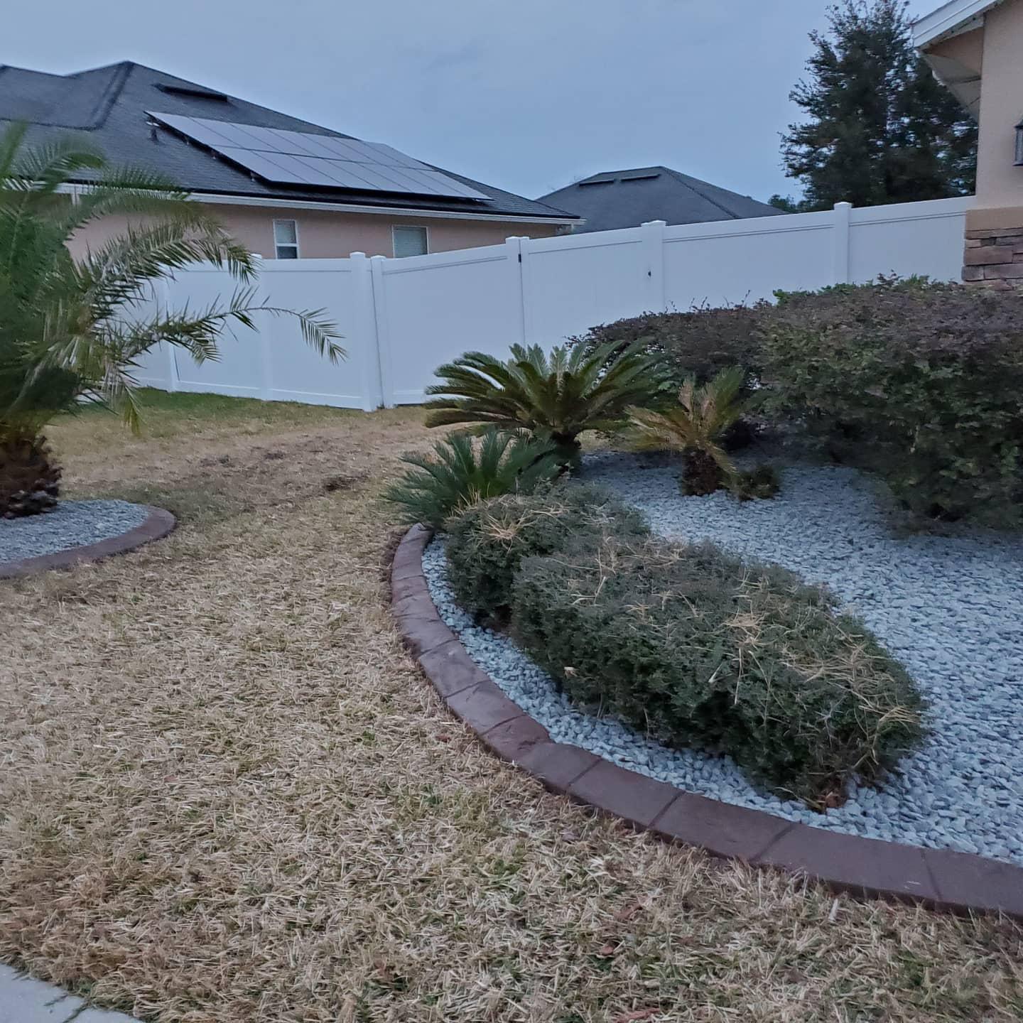 A backyard with a white fence and a garden