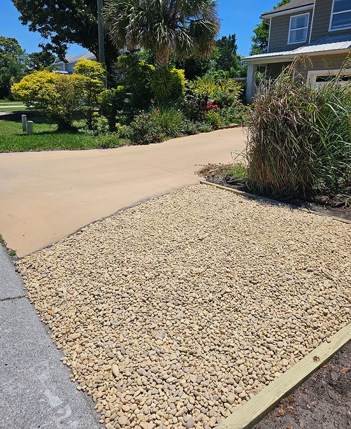 A gravel driveway leading to a house on a sunny day.
