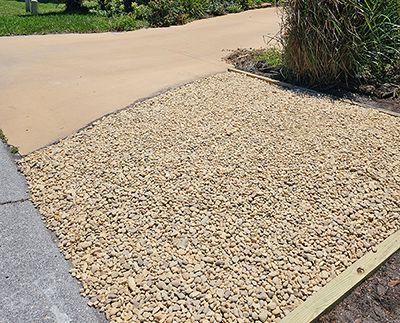 A gravel driveway with a concrete curb and a wooden border.