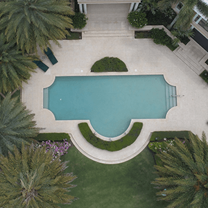 An aerial view of a large swimming pool surrounded by palm trees