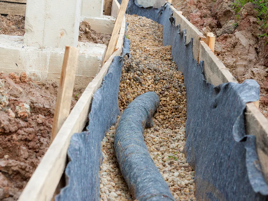 A pipe is being installed in a trench filled with gravel.