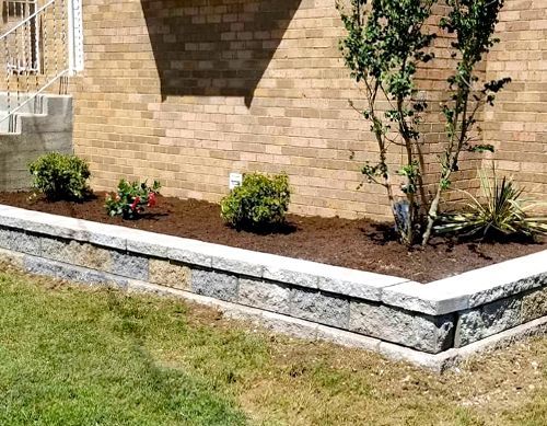 A brick wall with a planter in front of a house.