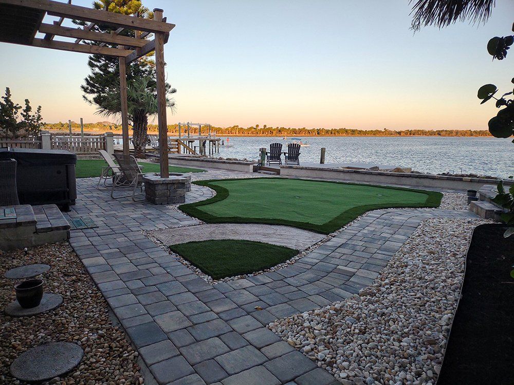 A patio with a putting green and a view of the water.