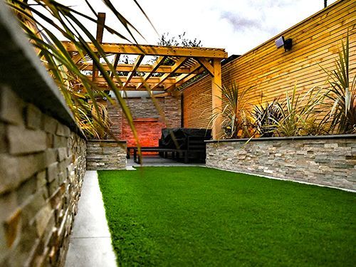 A backyard with a pergola and a lush green lawn.