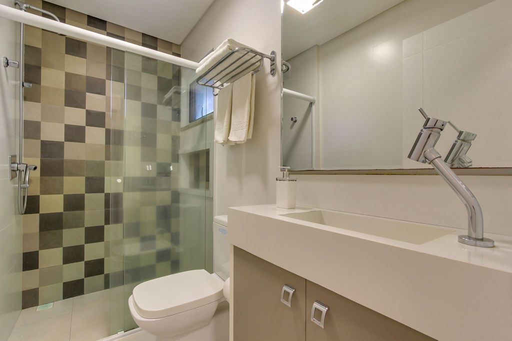 Banheiro moderno com chuveiro estampado, vaso sanitário branco e pia de bancada.