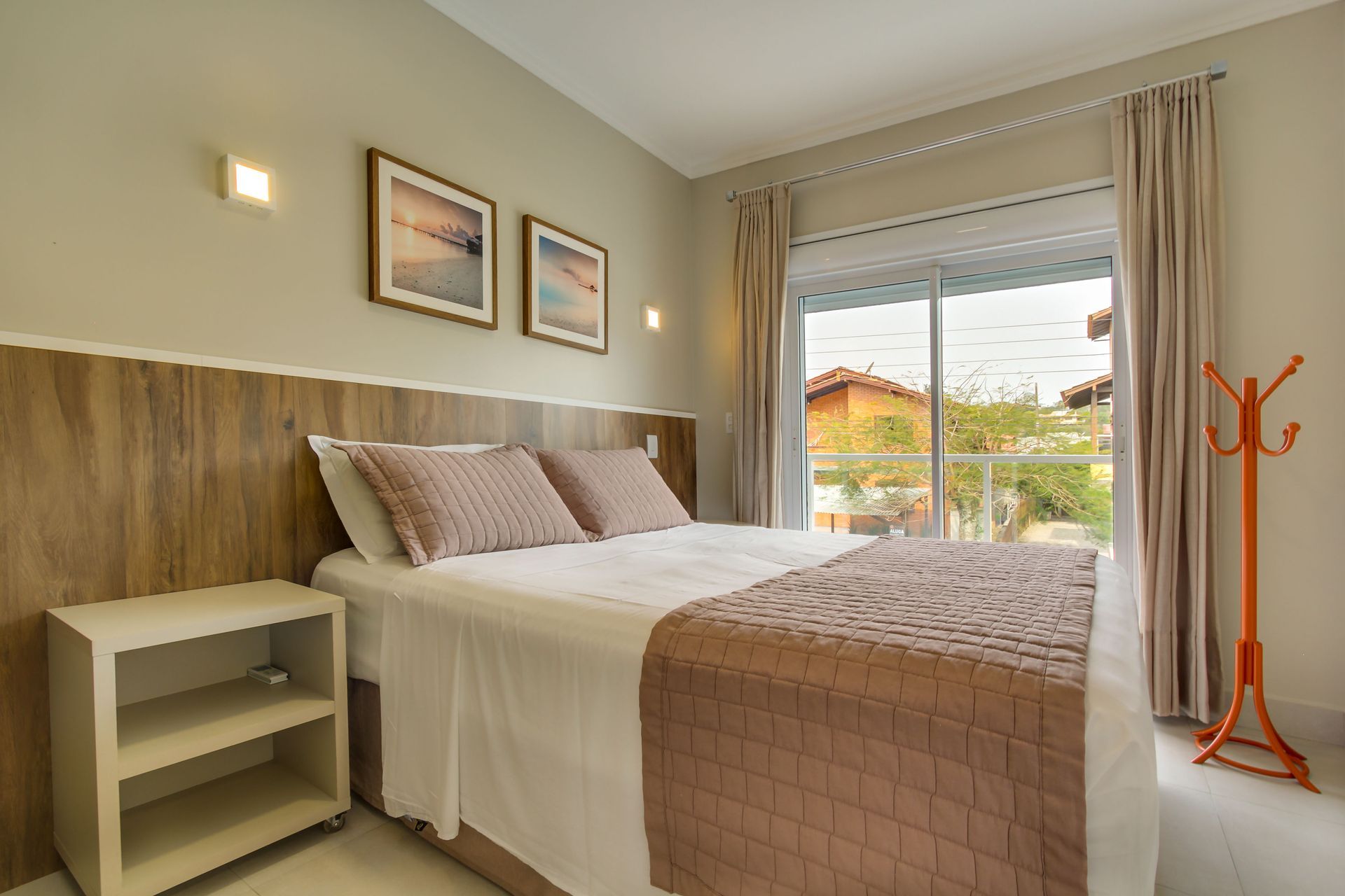 Quarto com cama, mesa de cabeceira e janela. Decoração em tons terrosos.