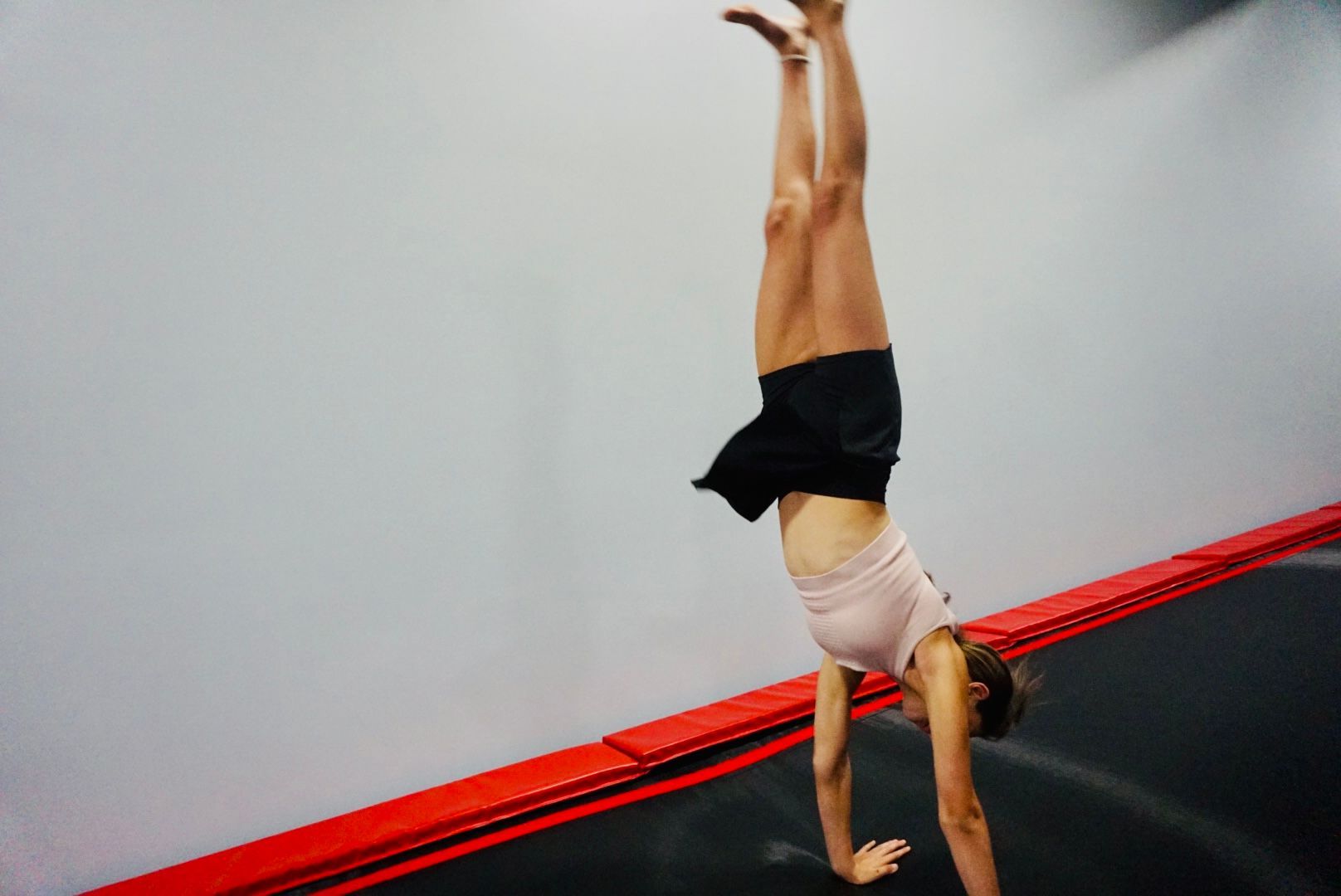 A woman is doing a handstand on a trampoline