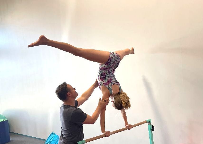 A young girl is standing on a balance beam in a gym.