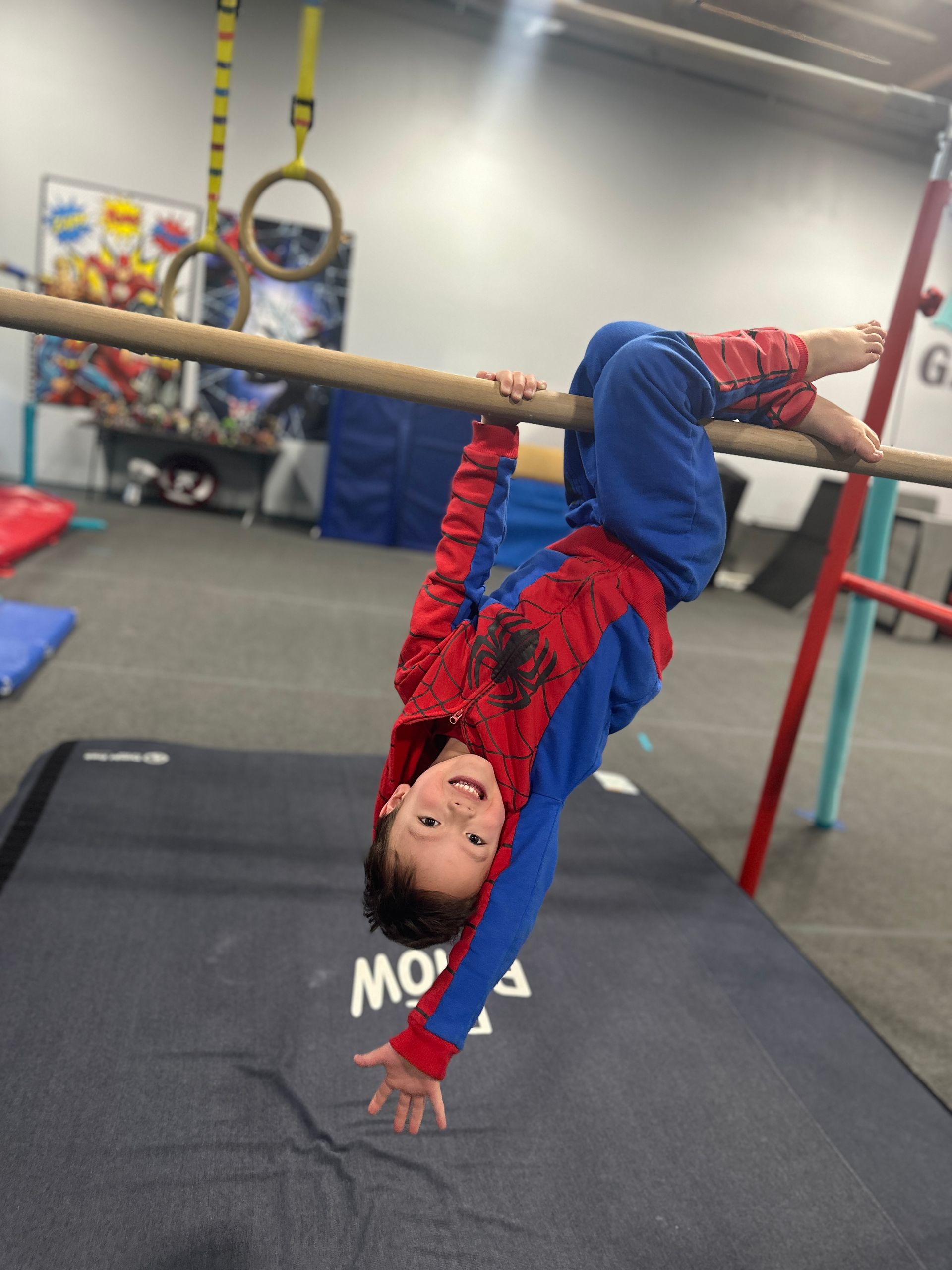 A young boy is doing a handstand on a bar in a gym