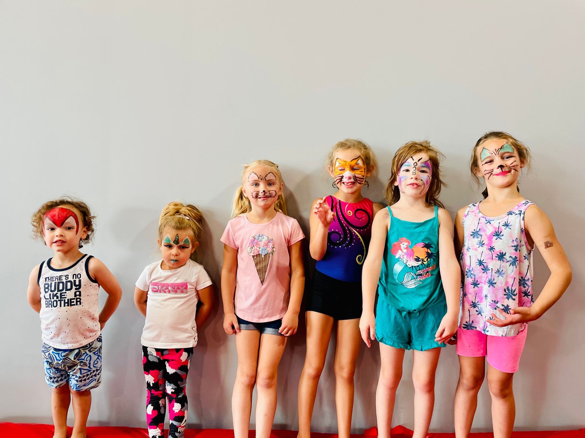 A group of young girls with their faces painted are standing next to each other.