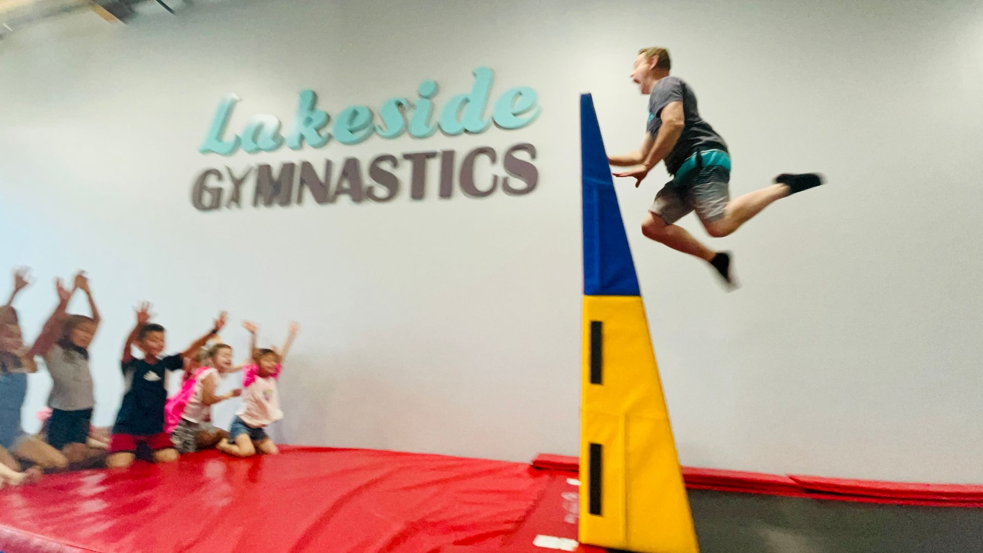 A group of children are playing on a trampoline in a gym.