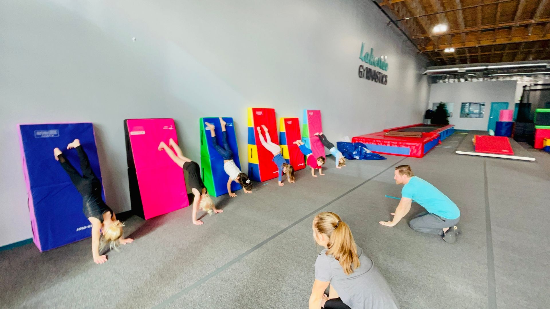 A group of people are doing handstands in a gym.