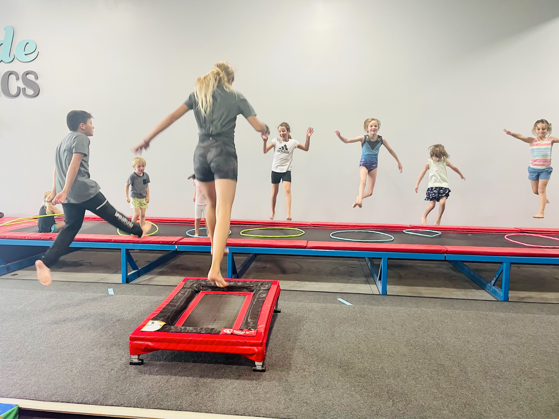 A group of children are jumping on trampolines in a gym.