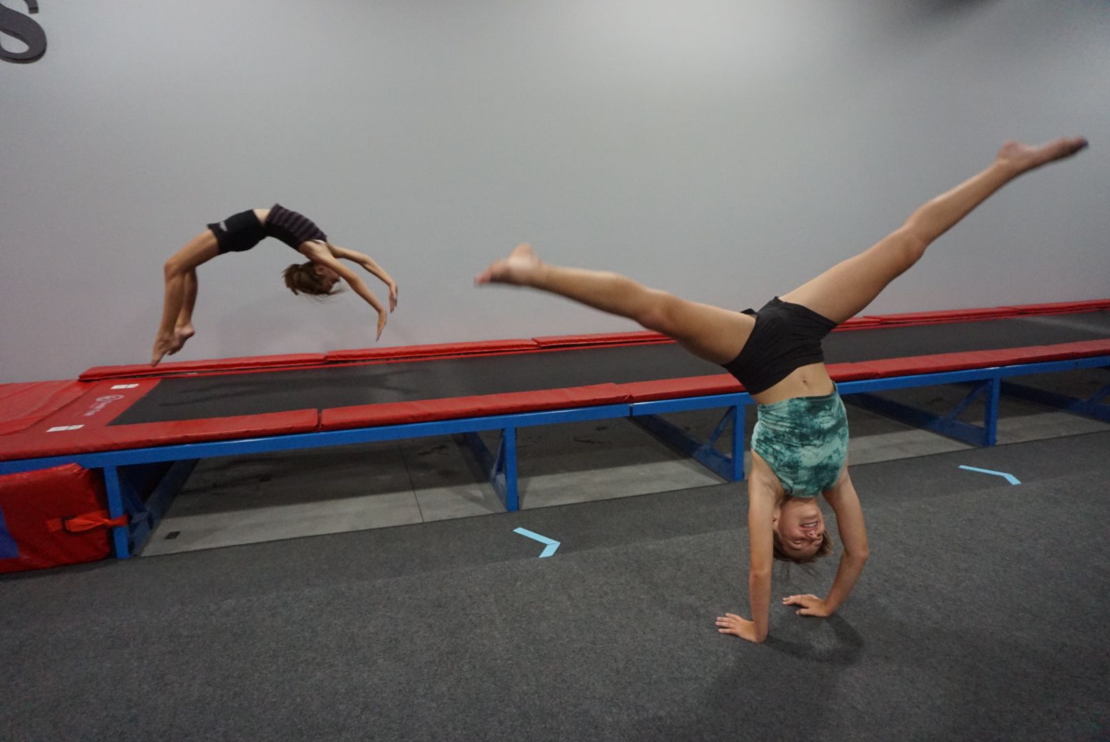 Two young girls are doing handstands on a trampoline.